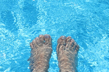 A woman's feet under water in a beautiful clear water pool creating ripples in Egypt