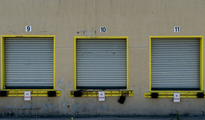 Three loading dock closed door for trailer trucks in empty parking lot building