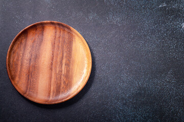Round wooden plate on a black background. Copy space