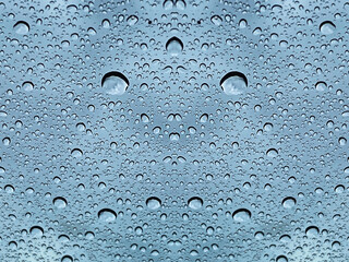 Raindrops on a glass pane with dark rain clouds in the background