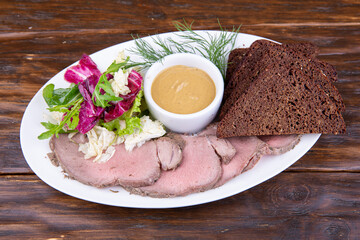 Boiled balyk, served with greens, black bread and mustard