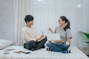 Happy young asian woman and her male gay friend working together at home.