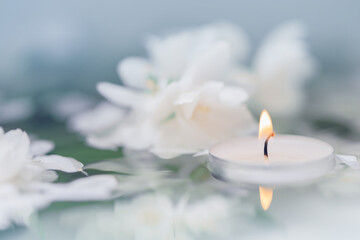 Obraz na płótnie Canvas White candle with flowers float on the surface of the water. Focused on the flame of the candle. SPA. CloseUp. Macro, Defocused. ReflectiCloseUp. Macro, Defocused. Focused on the flame of the candle.