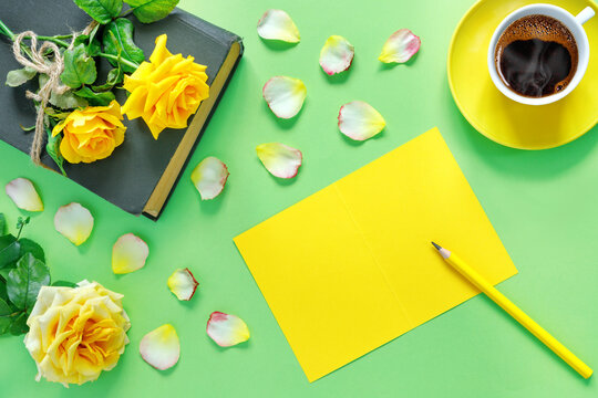 Bouquet of beautiful yellow roses with stack of old vintage books and hot coffee on peaper green  background.