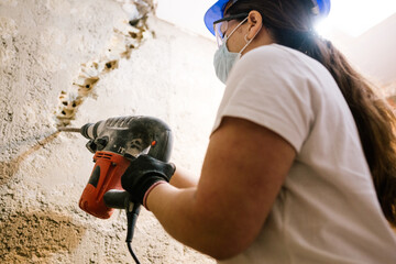 woman with a drill breaking a wall