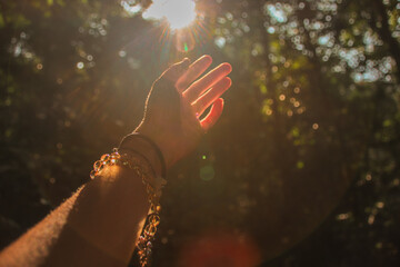 Hands reaching out to the light coming from the forest to show concept of mental health, hope and...