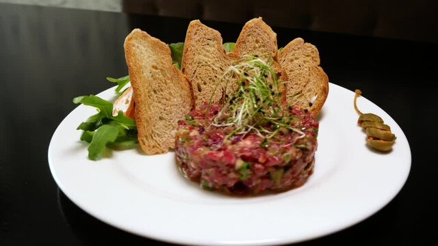 Raw tartar meat with spices, croutons and herbs. Beef tartar with capers. Beef tartar with slices of bread.  Raw meat tartare for gourmet meat.
