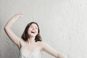 Fototapeta na wymiar happy brunette teenager girl on background white wall