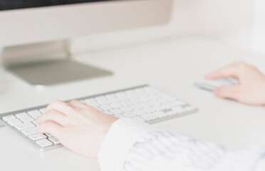 Woman's hands using a wireless computer keyboard and mouse, in front of the computer screen at her desk. Business woman, selective focus, concepts