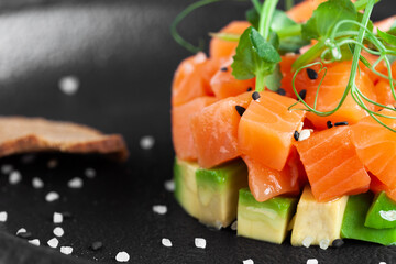 Portion of appetizer tartar made from chopped fresh salmon fish, avocado