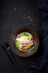 Fish dish decorated with flowers on black background