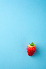 One fresh red strawberry on blue background
