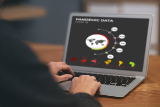 Woman with laptop checking pandemic data indoors, closeup. Coronavirus outbreak