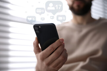 Man using modern smartphone indoors, closeup. Social media marketing