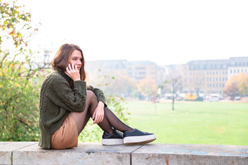 Young woman talks on cell phone sitting in park