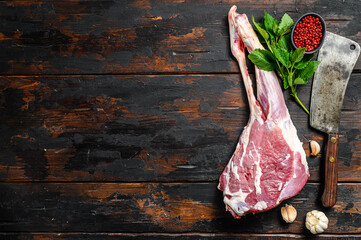 Whole raw leg of lamb. Fresh organic meat. Dark wooden background. Top view. Copy space