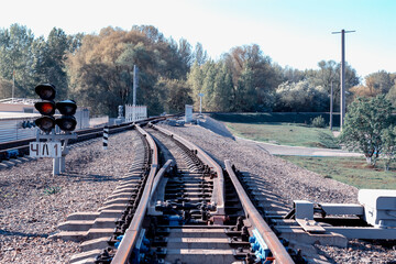 Red traffic light burns at the empty train tracks