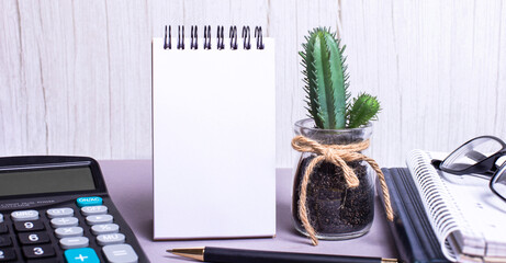 On the desktop, a calculator, diaries, pen, blank notebook, flower and glasses. Place to insert...