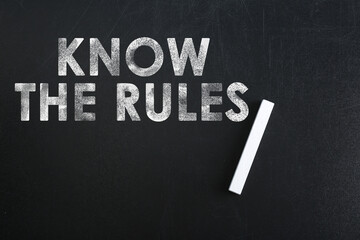 Phrase Know the rules and piece of chalk on blackboard, top view
