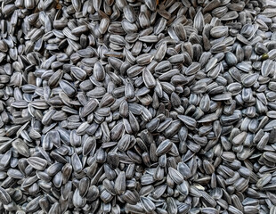 Black sunflower seeds on the counter of a farmers market. Abstract background texture of sunflower seeds. Top view. 