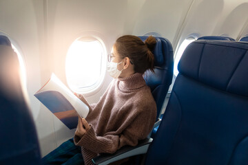A young woman wearing face mask is traveling on airplane , New normal travel after covid-19...