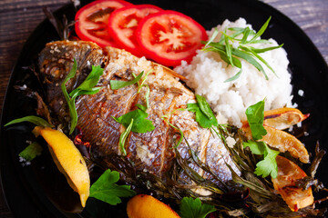 Baked dorada fish with lemon, parsley, rosemary and tomatoes