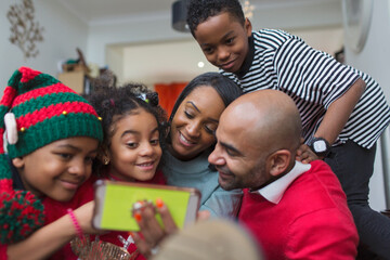 Happy family taking Christmas selfie with smart phone