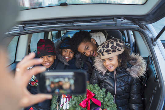Happy family with Christmas wreath posing for photo in car