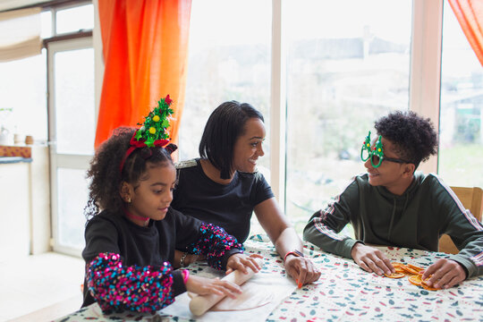Happy mother and sons making Christmas cookies at table