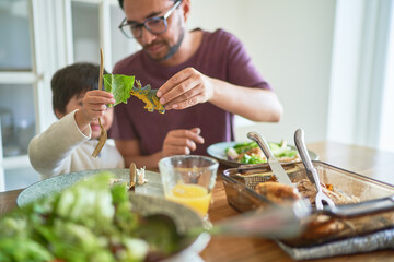 Playful father and son eating with toy dinosaur