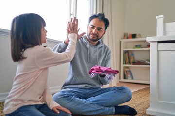 Father and daughter folding laundry and high fiving