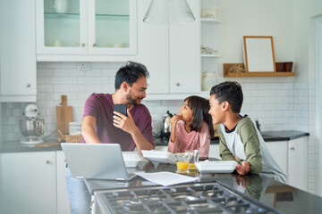 Father working in kitchen with kids eating takeout food