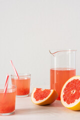 Summer refreshing grapefruit drink, jug and glasses with grapefruit pulp and juice and straws