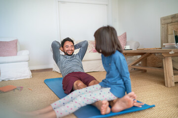 Playful father and daughter exercising in living room