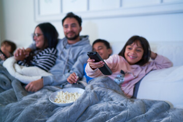 Family relaxing on sofa and watching TV with popcorn