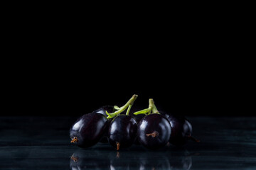 Black currants on a black background. Two brushes of black currant lie next to each other