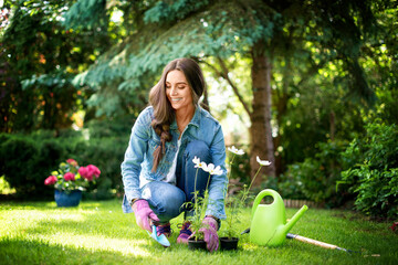 Happy young woman planting flowers in the garden