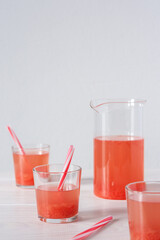 Summer refreshing grapefruit drink, jug and glasses with grapefruit pulp and juice and straws