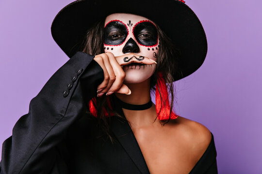 Funny latin girl in sombrero having fun in halloween. Cute female model in black mexican hat celebrating day of the dead.