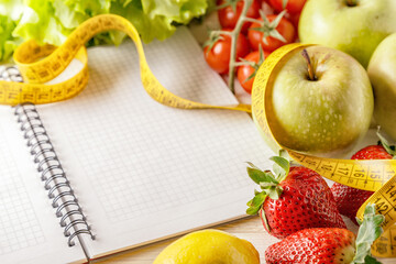 Fresh organic vegetables and fruits, open blank notebook and pen on wooden background.