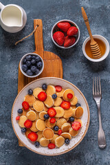 Tiny pancakes with strawberries and blueberries for breakfast.