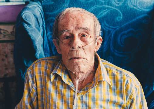 Portrait of an old man sitting at home with oxygen in his nose.