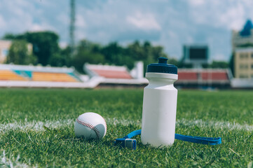Sports water bottle with a whistle and a baseball ball in a green stadium.