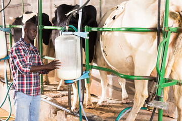 Portrait of farmer man staning near cow milking machines indoor at farm