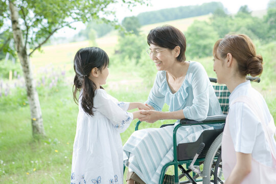 孫の手を握る60代の女性と見守る女性介護士