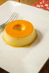 Milk Pudding or Pudim de leite. Brazilian dessert homemade caramel custard pudding. Traditional brazilian flan on wooden background.