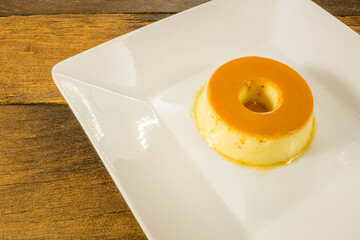 Milk Pudding or Pudim de leite. Brazilian dessert homemade caramel custard pudding. Traditional brazilian flan on wooden background.