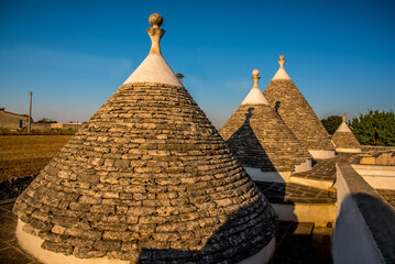 Fototapeta na wymiar Conical limestone roofs of traditional Trulli houses near Martina Franca, Bari, Italy in the summertime