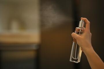 Woman spraying air freshener at home, closeup. Space for text