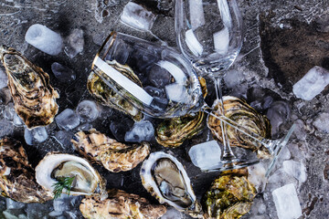 top view of delicious oysters on ice cubes and wine glass